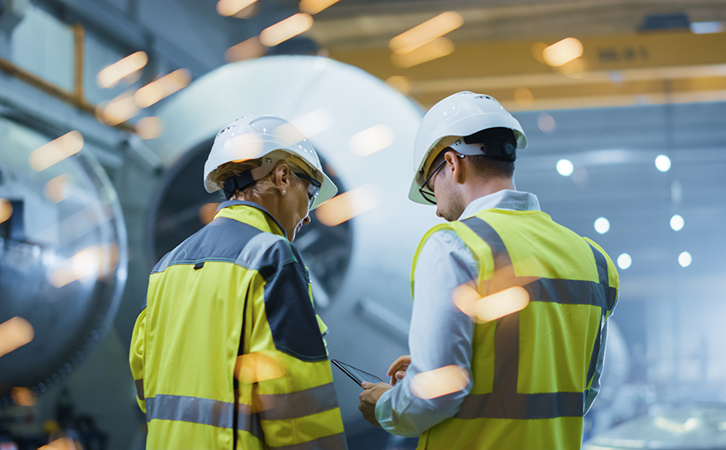 Two engineers discussing a project in a manufacturing setting.