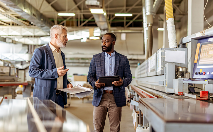 Two men discussing specifications in a manufacturing facility